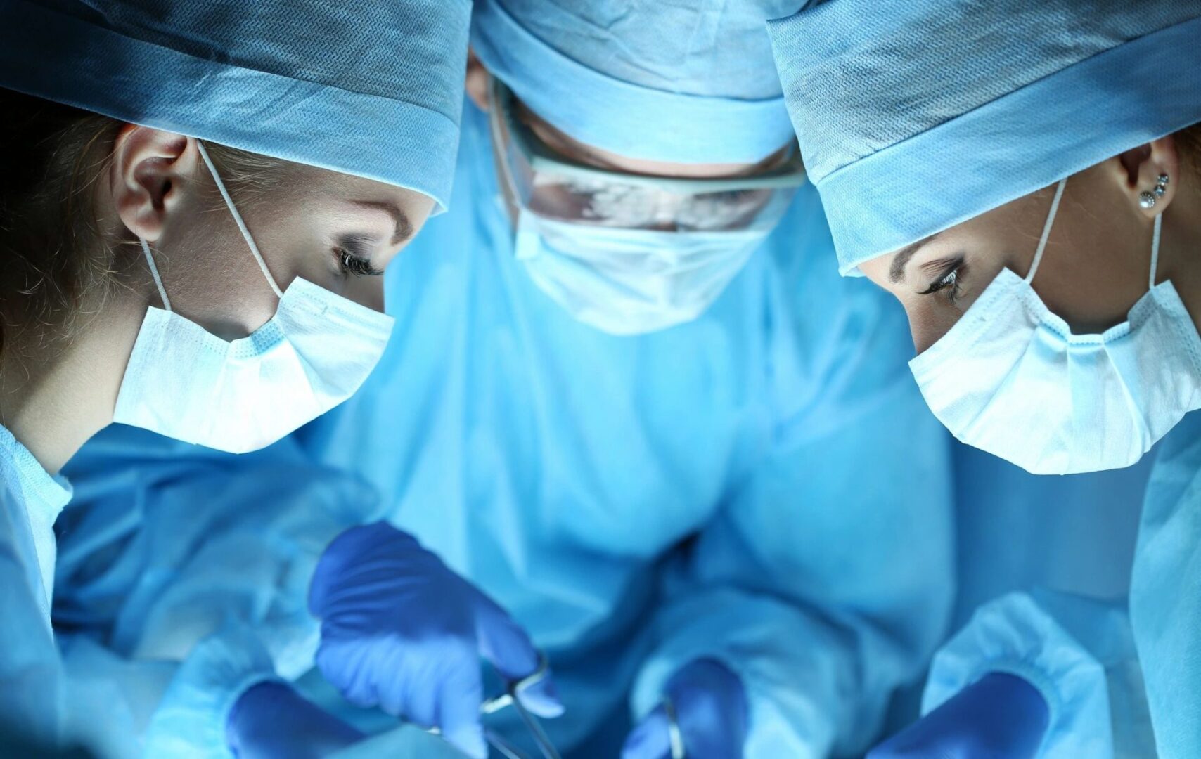 A group of surgeons in blue gowns and masks.