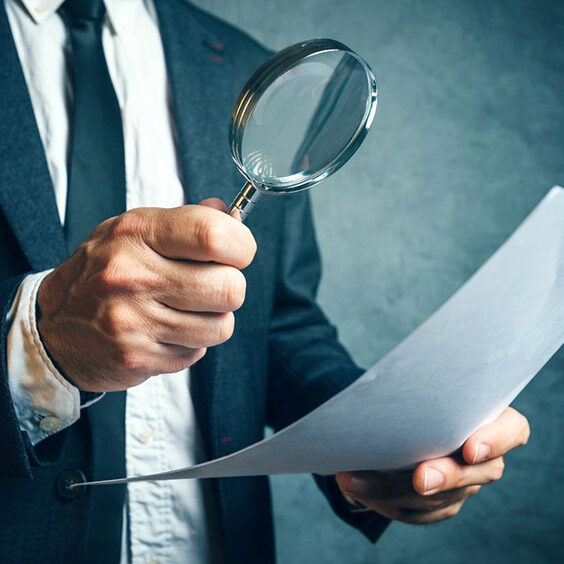 A man holding a magnifying glass and paper.