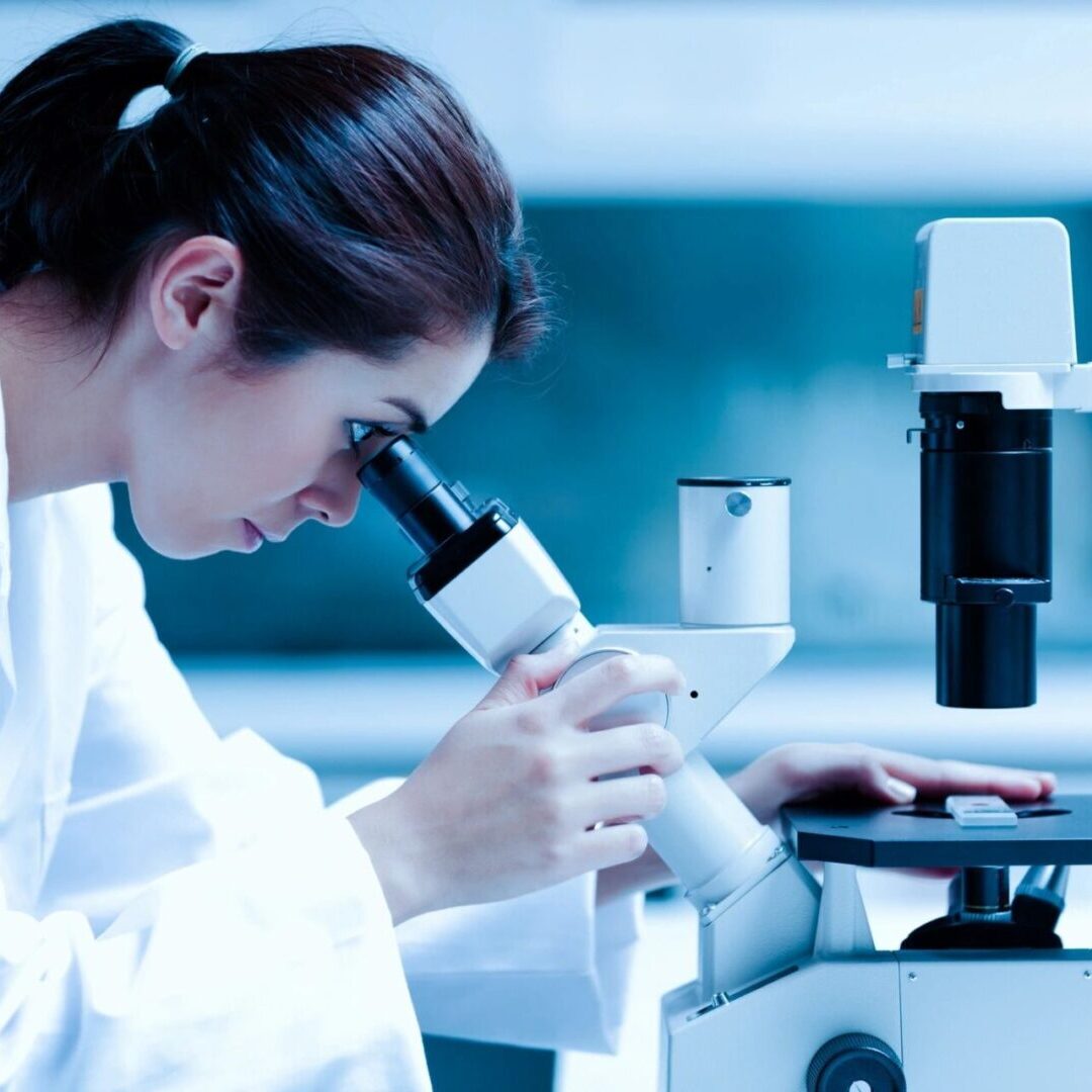 A woman looking through a microscope in a lab.